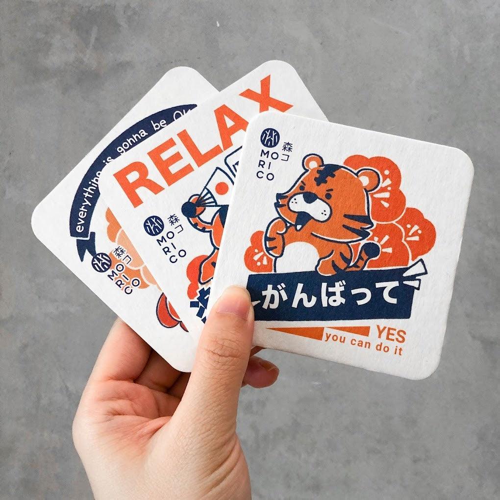 Image of high-quality coaster paper prints with a logo in full color. The coasters are available in sizes 7x7 cm, 8x8 cm, 9x9 cm, and 10x10 cm, each featuring a sturdy 2mm backing for durability. The image showcases the vibrant colors and professional finish achieved through offset printing.