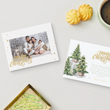 Two Christmas cards on a table with a mug of coffee and cookies.